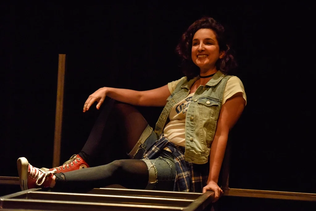 Comédienne souriante posant sur la structure de la scène.